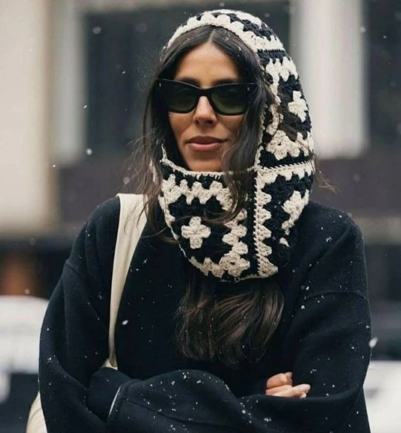 Sort og hvid granny square balaclava båret med solbriller og sort frakke